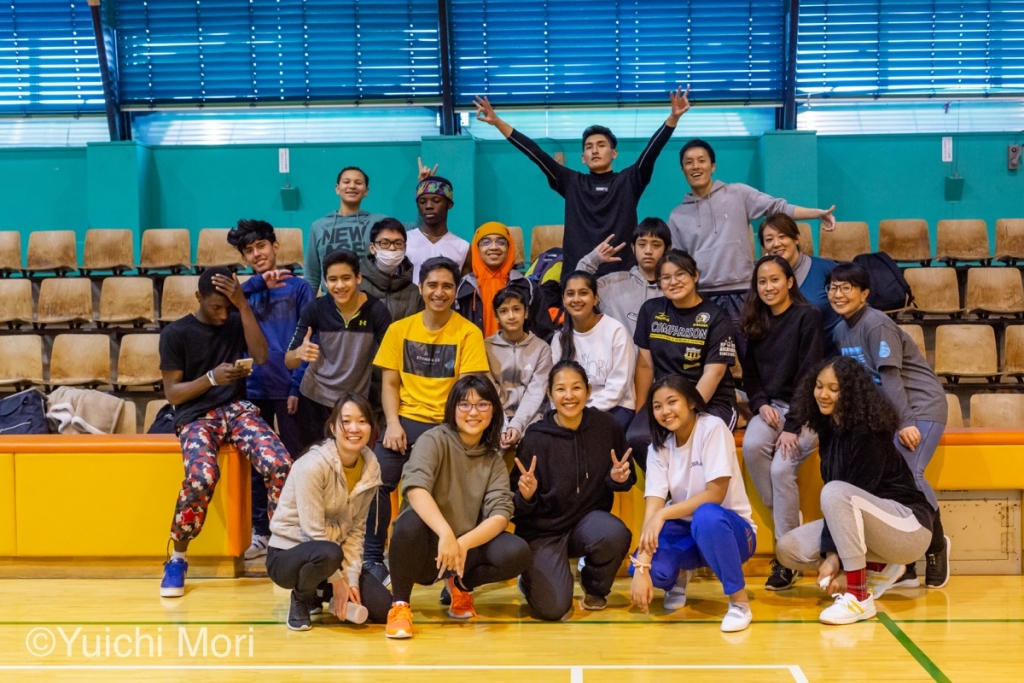 YSCグローバル・スクールのダンスワークショップ。体育館に約２０人の海外にもルーツを持つ男女の学生たちが集まって、フィリピン人ダンサーの先生を囲み、福岡さんやみんなで笑顔を見せている集合写真。