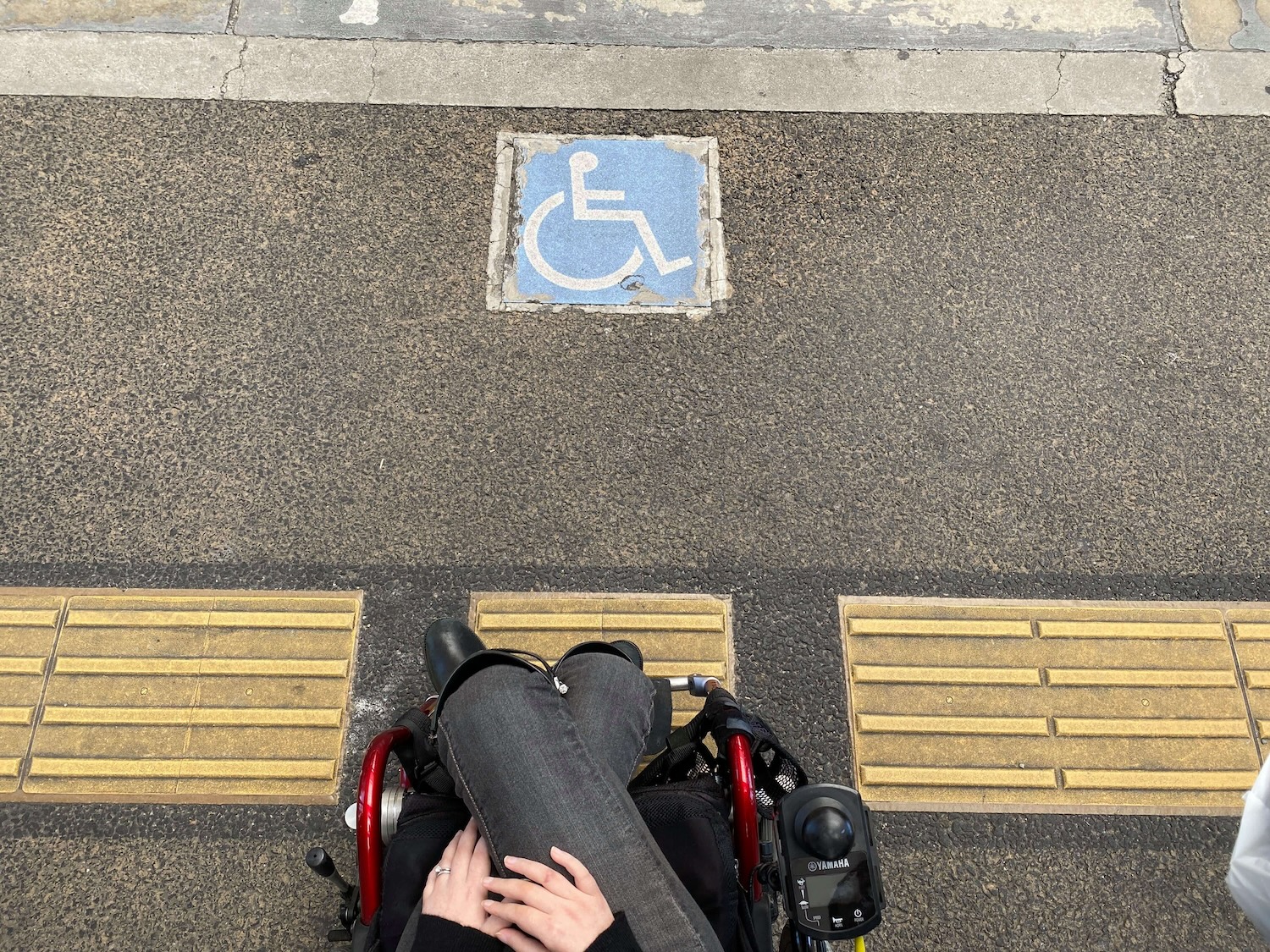 車椅子に乗った方が地面に敷かれた点字ブロックを見下ろす視点で撮られた写真です